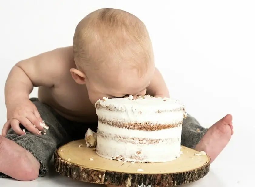 kid sitting beside round cake close-up photography